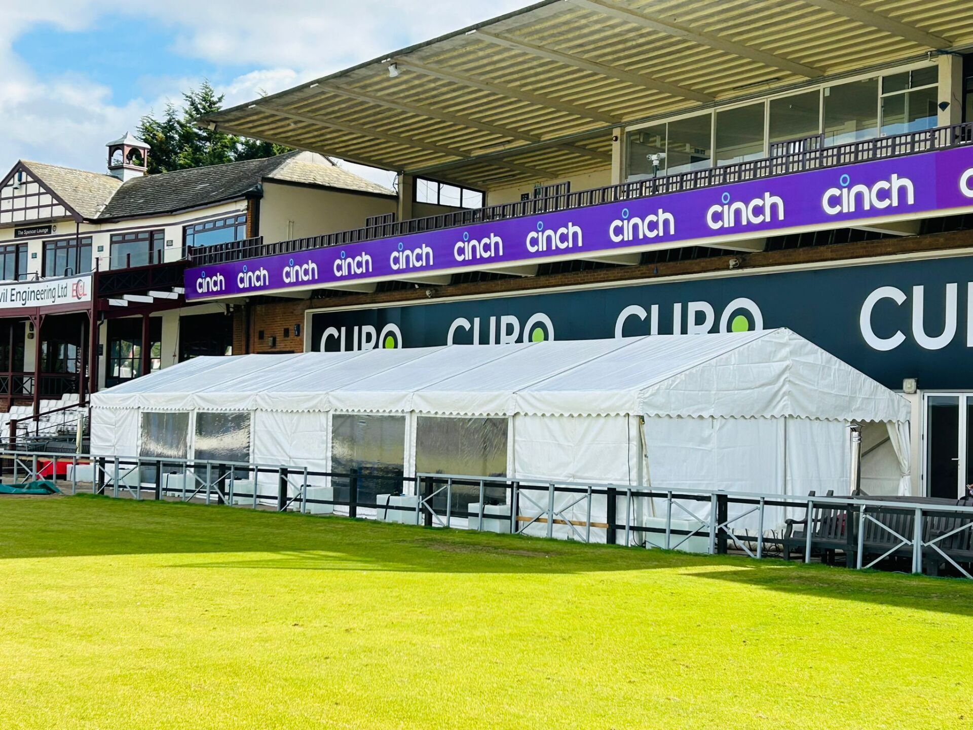 A row of white tents are sitting in front of a stadium.