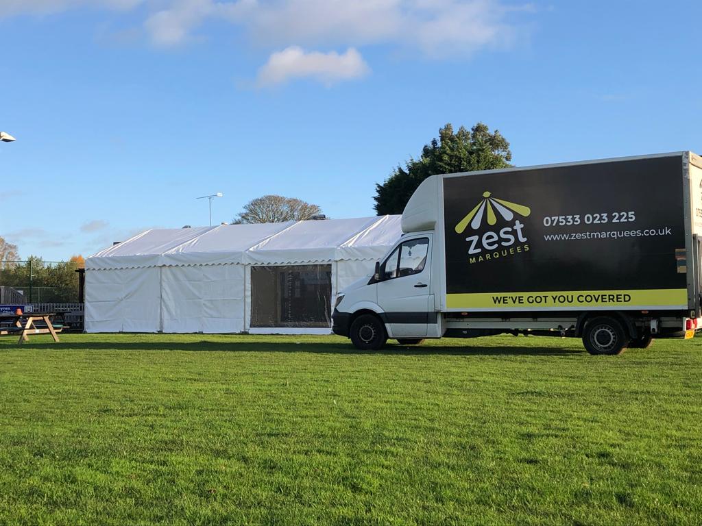 A zest truck is parked in a grassy field next to a tent.