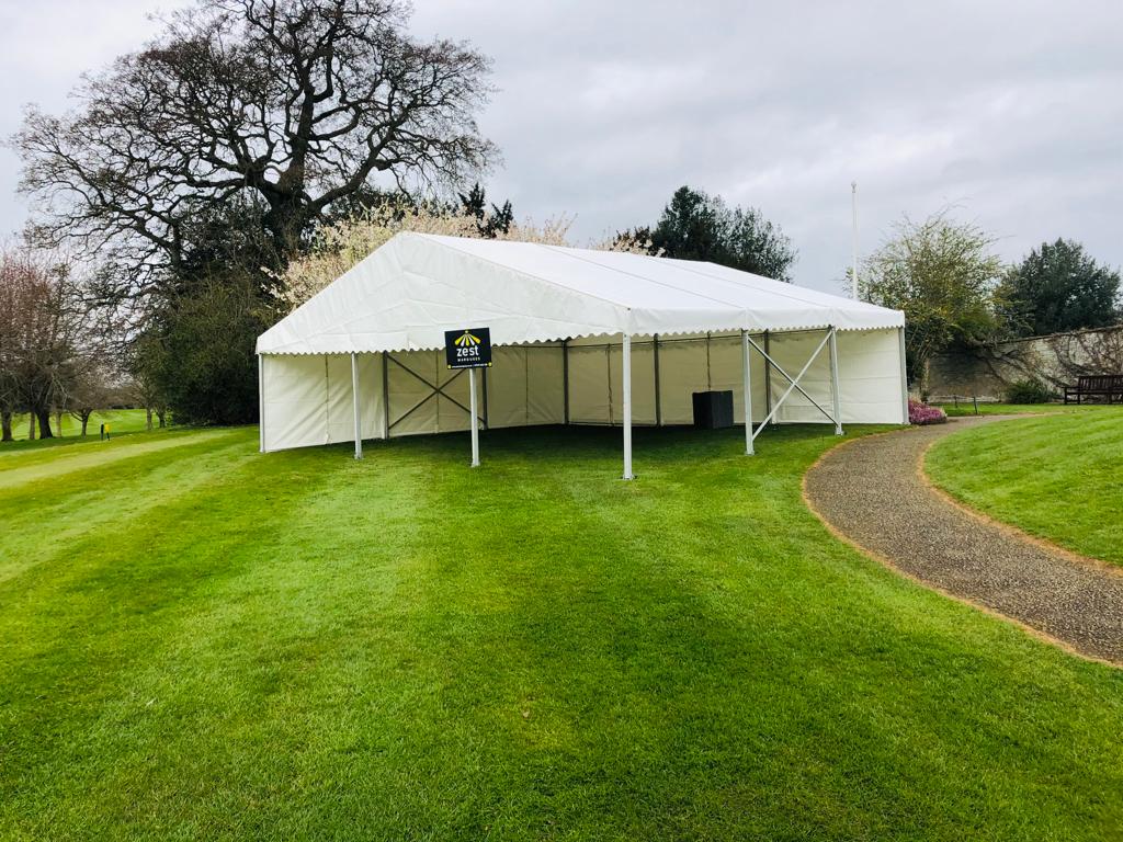 A large white tent is sitting in the middle of a lush green field.