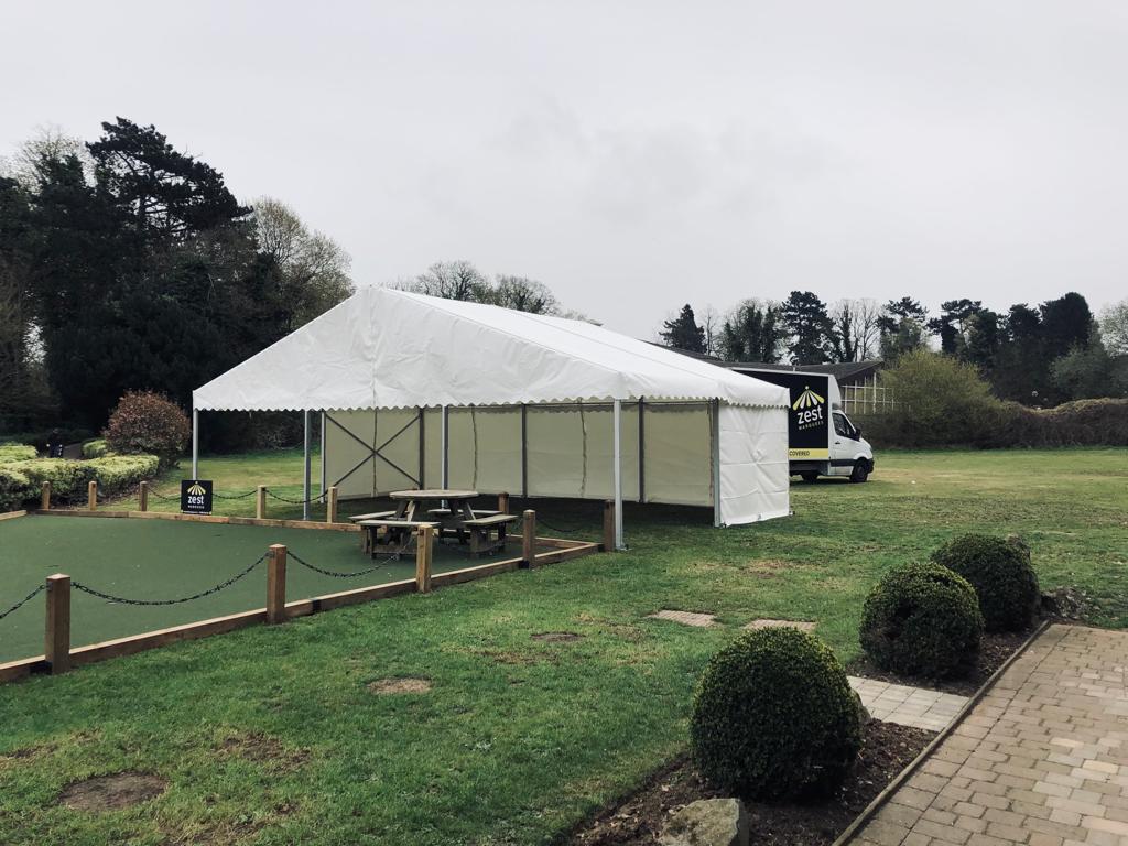 A large white tent is sitting in the middle of a grassy field.