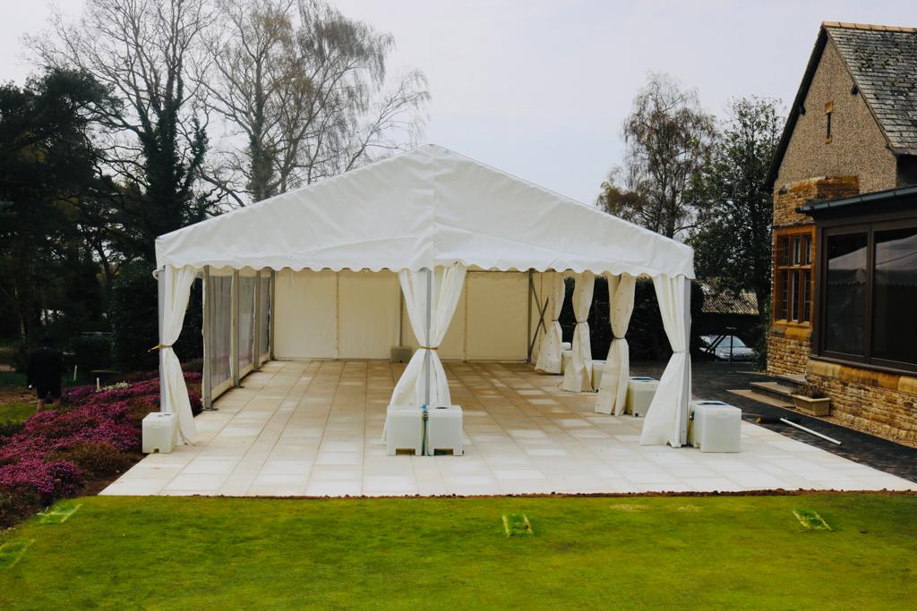 A large white tent is sitting on top of a lush green field.