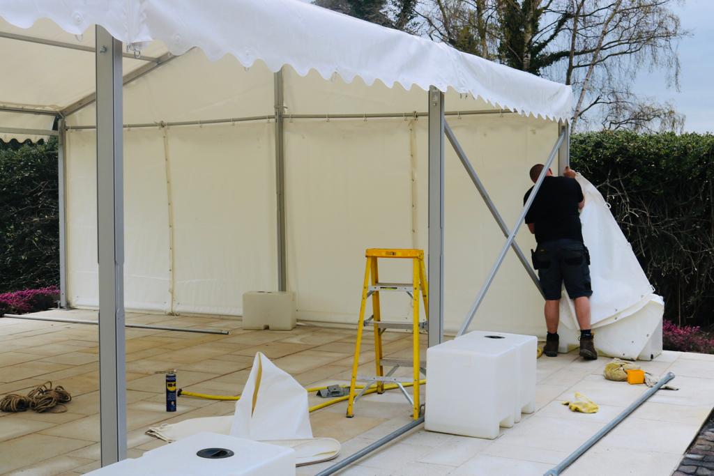 A man is standing in front of a white tent.
