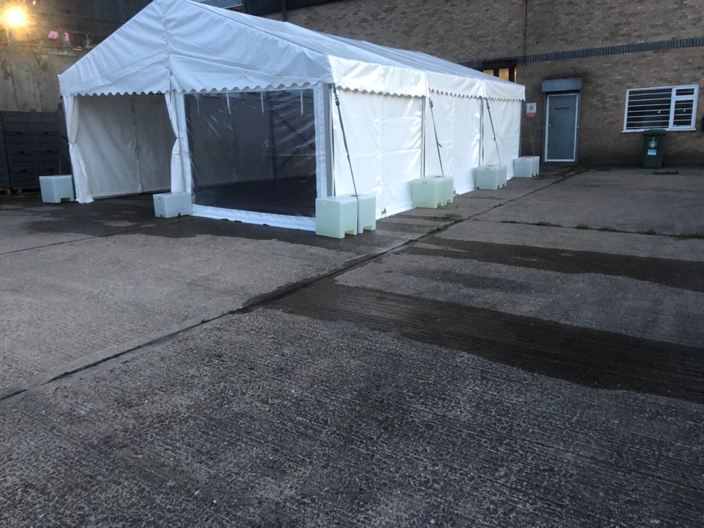 A large white tent is sitting in the middle of a parking lot