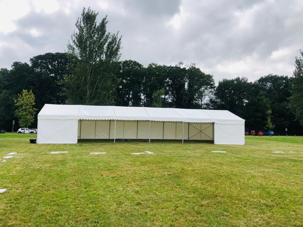 A large white tent is sitting in the middle of a grassy field.
