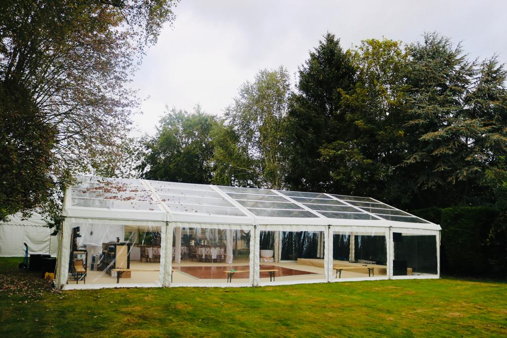 A large clear tent is sitting in the middle of a grassy field.