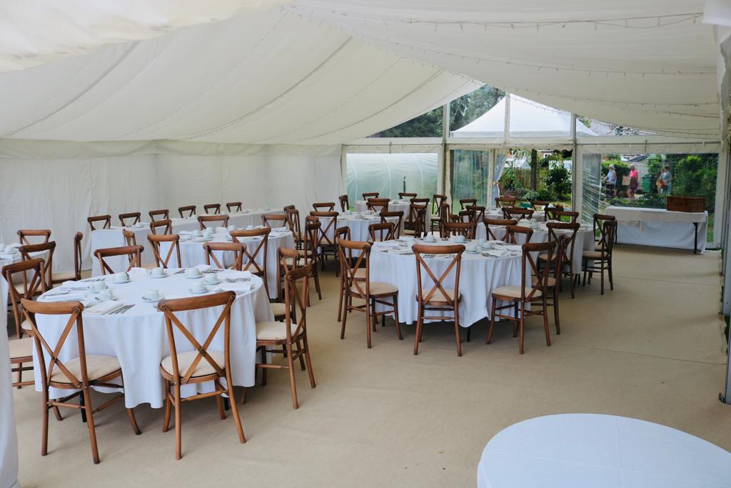 A large tent with tables and chairs set up for a wedding reception.