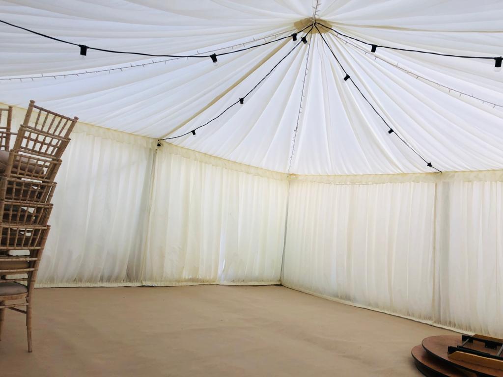 A row of chairs are sitting under a white tent.
