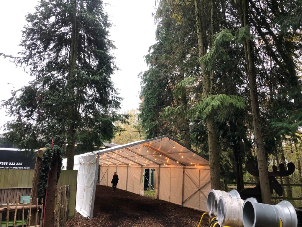 A white tent is sitting in the middle of a forest.