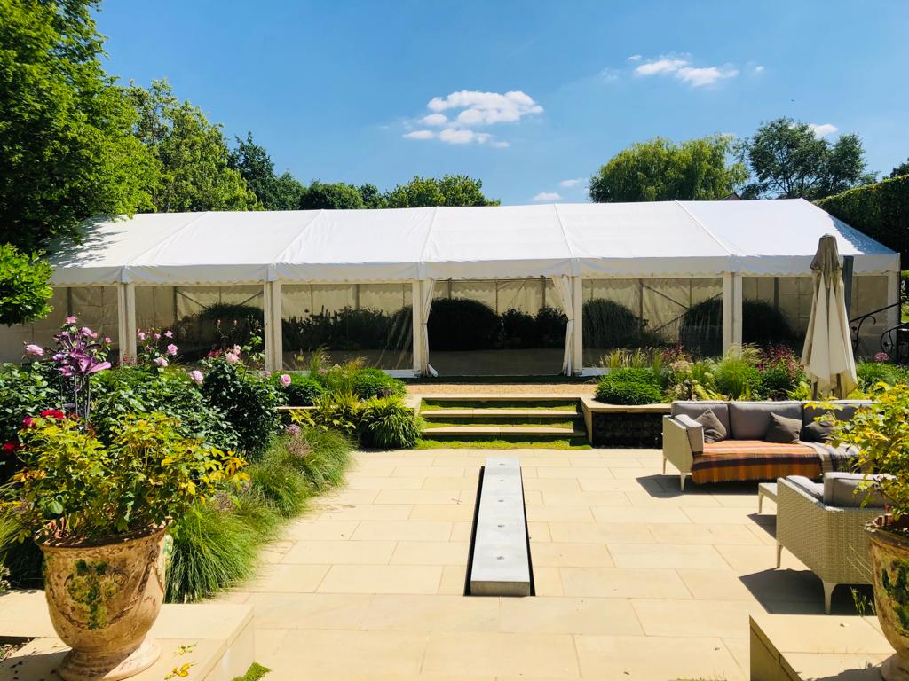 A large white tent is sitting in the middle of a garden.