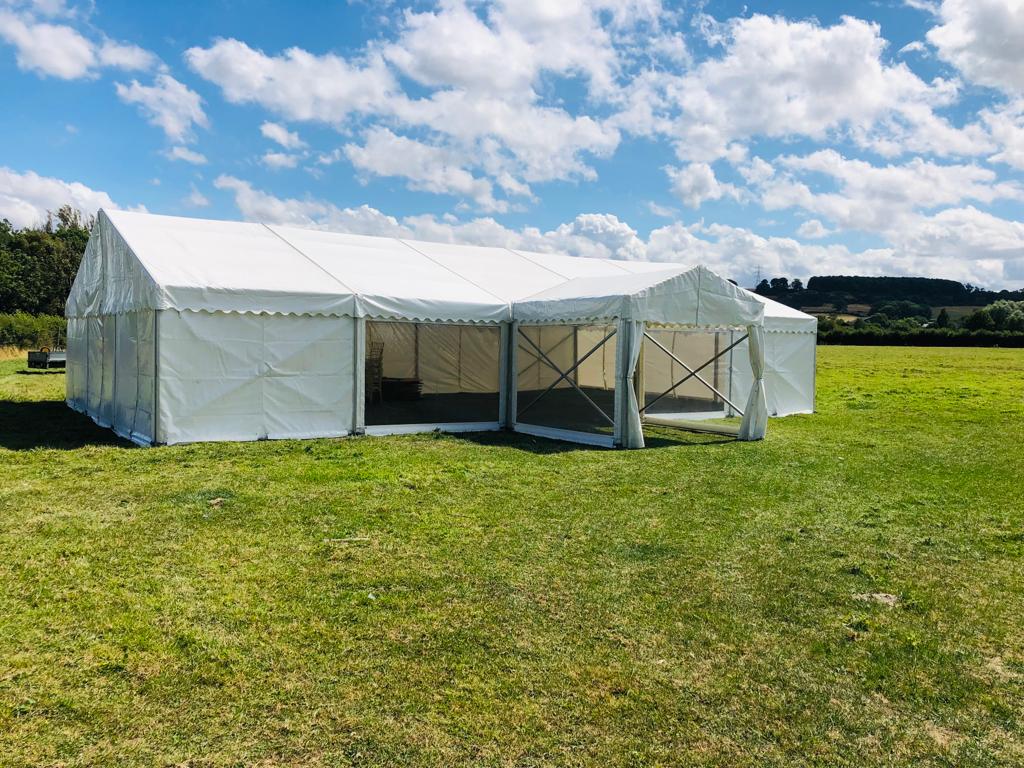 A large white tent is sitting in the middle of a grassy field.