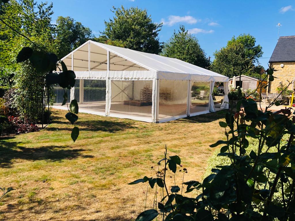 A large white tent is sitting in the middle of a grassy field.