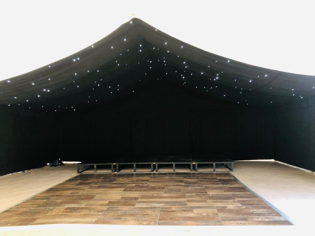 A black tent with a wooden dance floor underneath it.