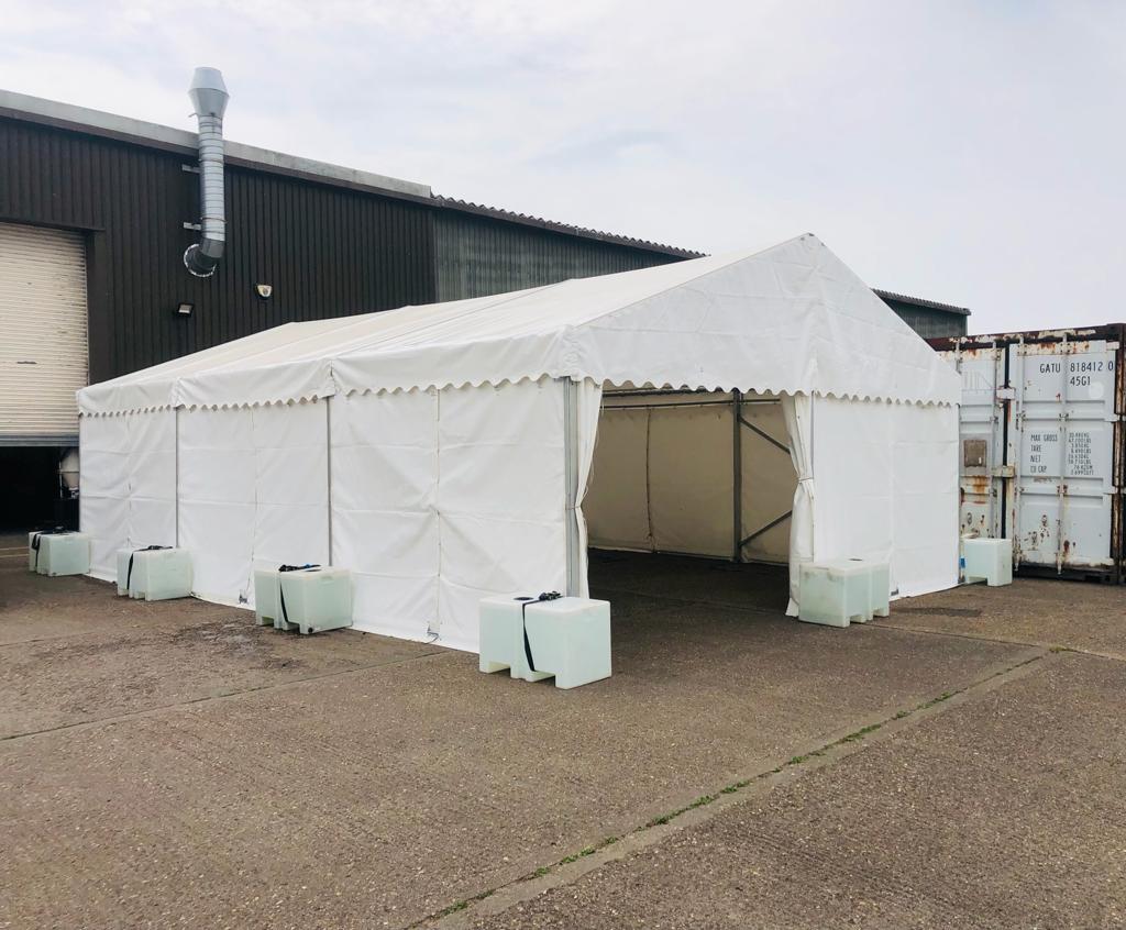 A large white tent is sitting in front of a building.