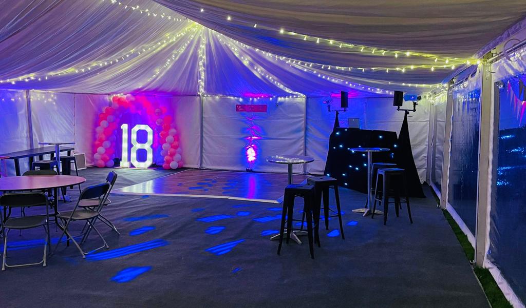 A large room with tables and chairs under a tent.