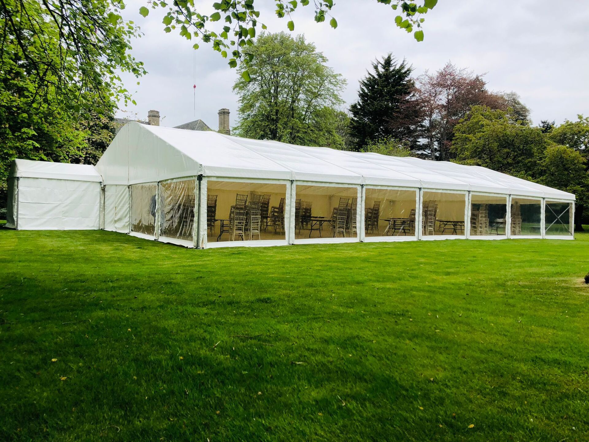 A large white tent is sitting in the middle of a lush green field.