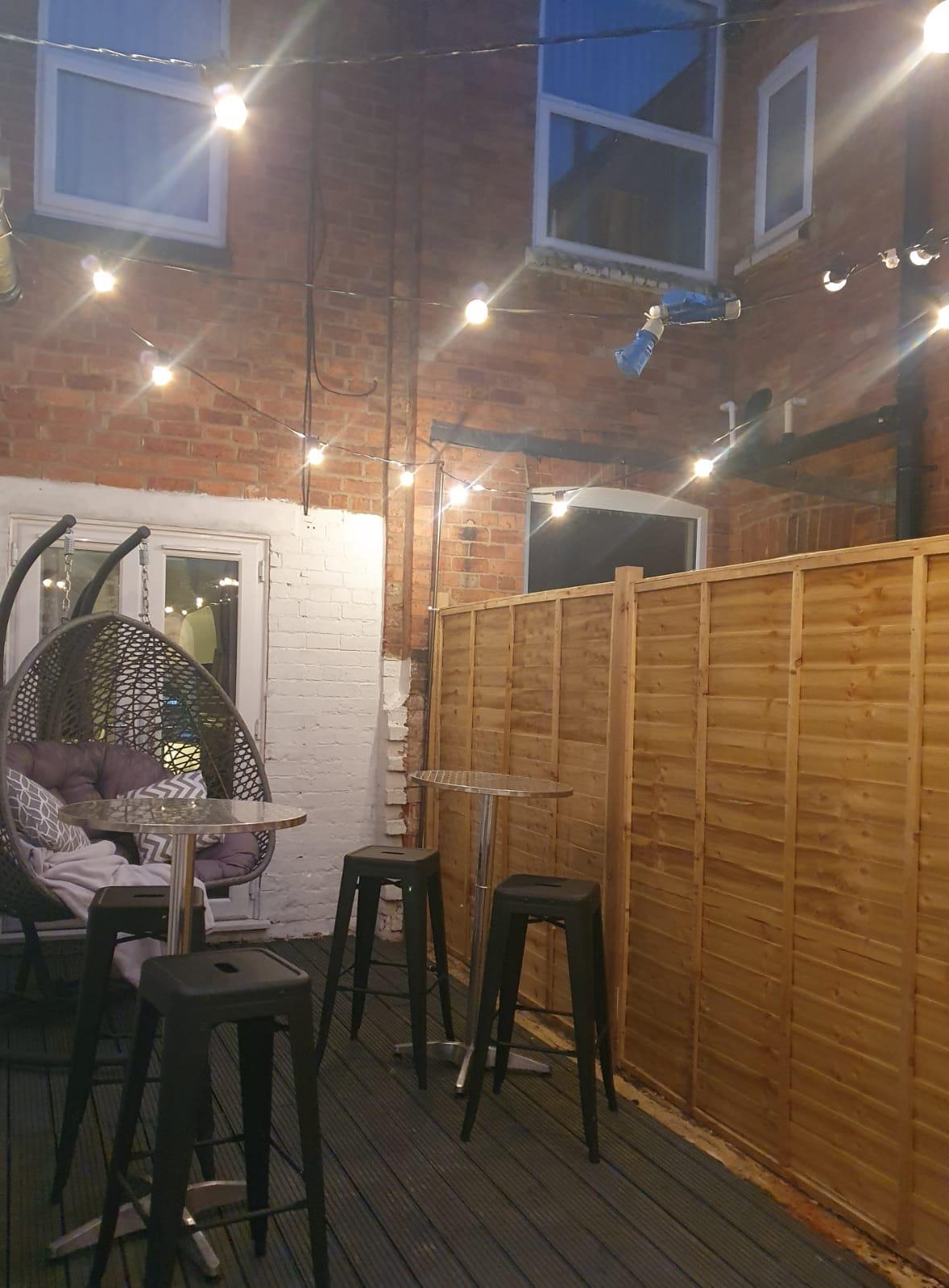 A patio with tables and chairs and a wooden fence.