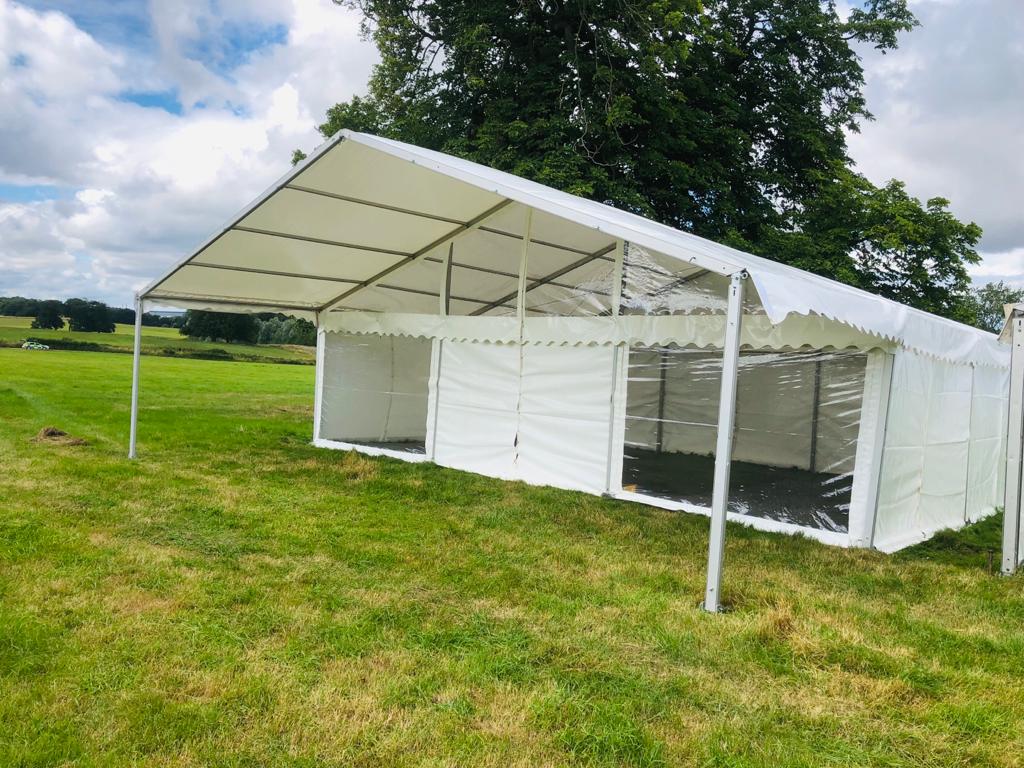 A large white tent is sitting in the middle of a grassy field.