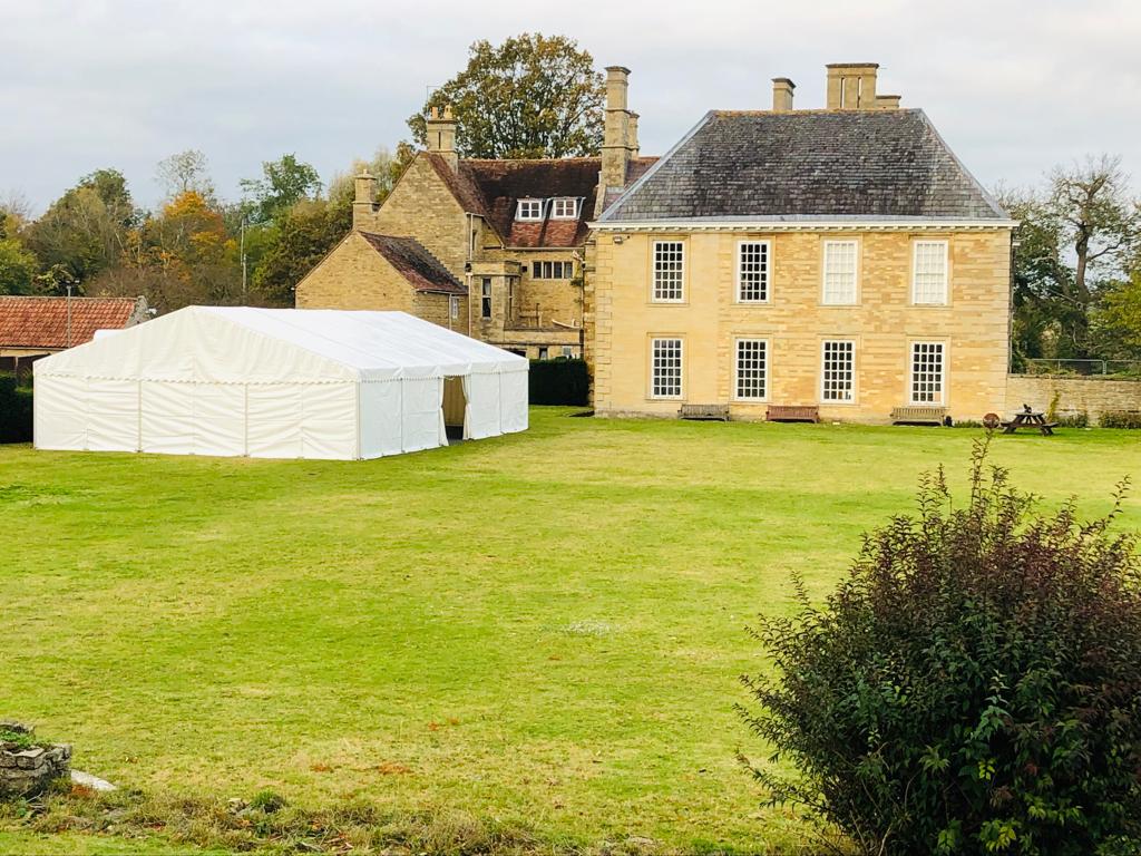 A large house with a white tent in front of it.