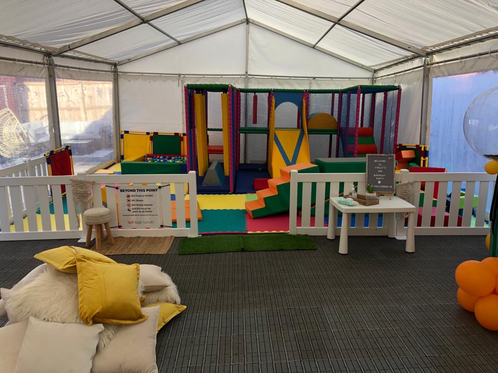 There is a playground inside of a tent with a table and chairs.