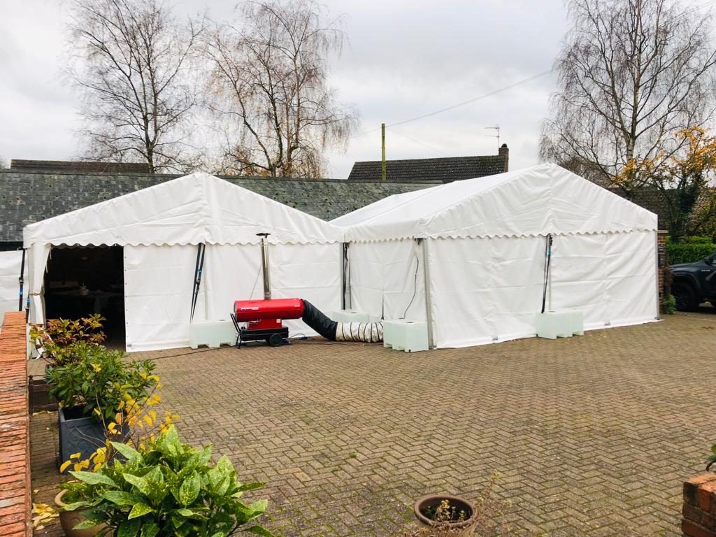 A group of white tents are sitting on top of a brick driveway.