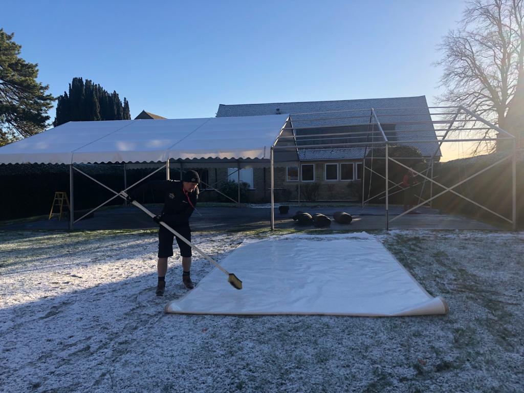 A man is standing in the snow holding a shovel.