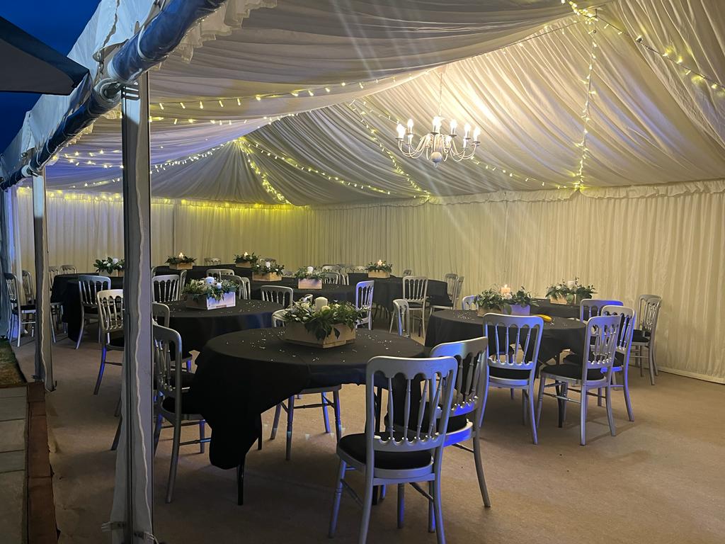 A large tent with tables and chairs set up for a wedding reception.