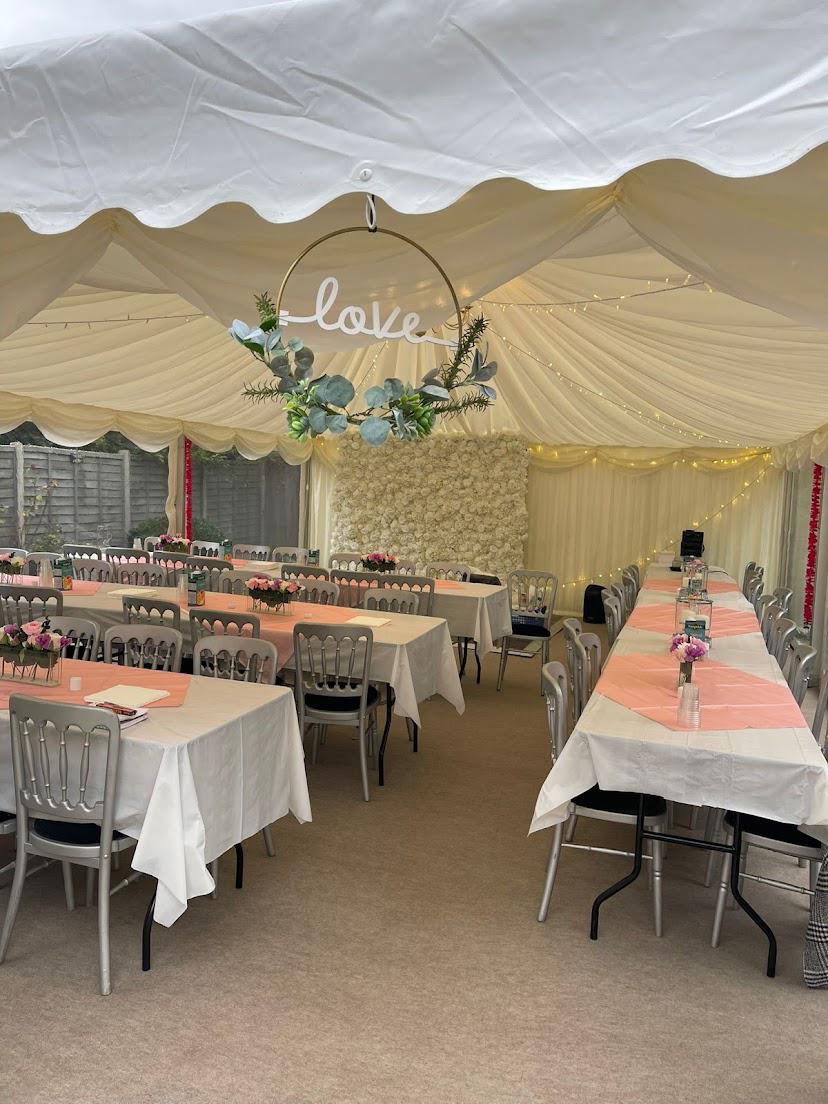 A large tent with tables and chairs set up for a wedding reception.
