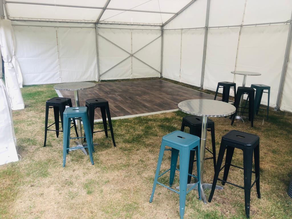 A tent with tables and stools inside of it.
