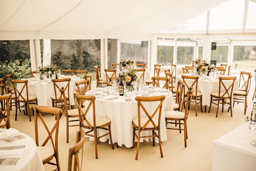 A large tent with tables and chairs set up for a wedding reception.