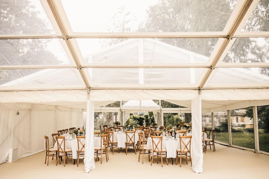 A clear tent with tables and chairs inside of it.
