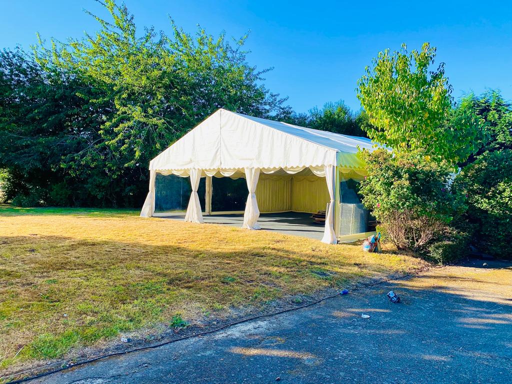 A large white tent is sitting in the middle of a field.