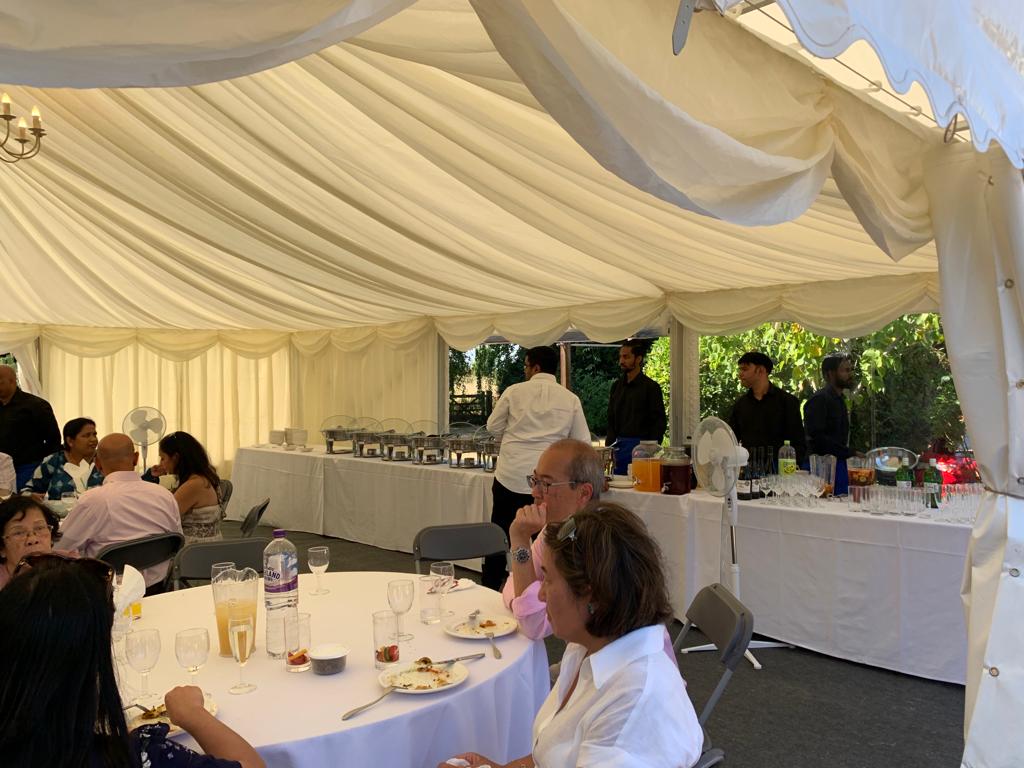 A group of people are sitting at tables under a tent.
