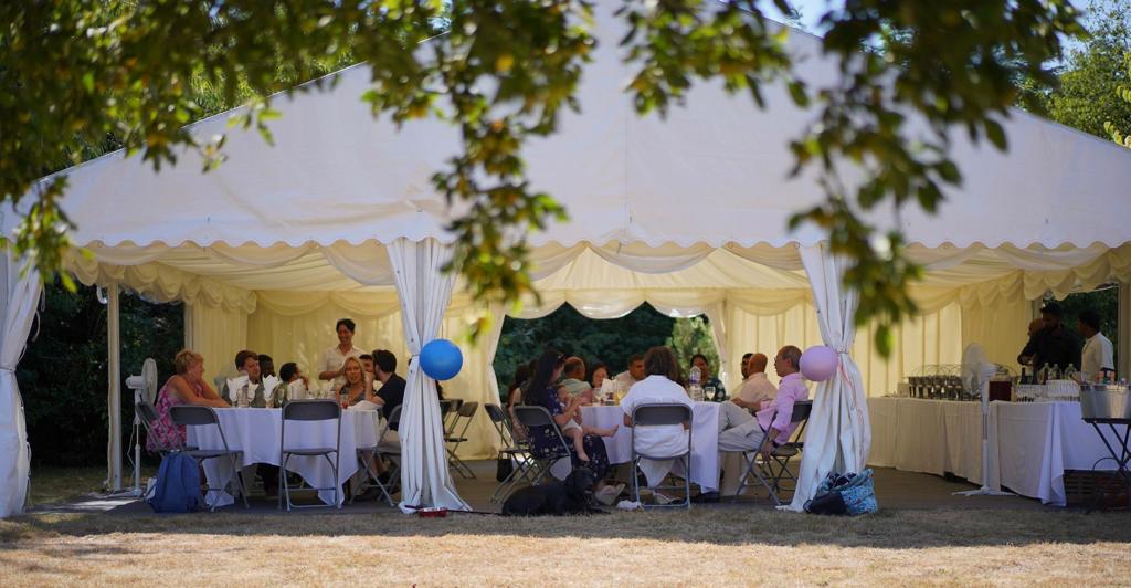 A group of people are sitting at tables under a tent.