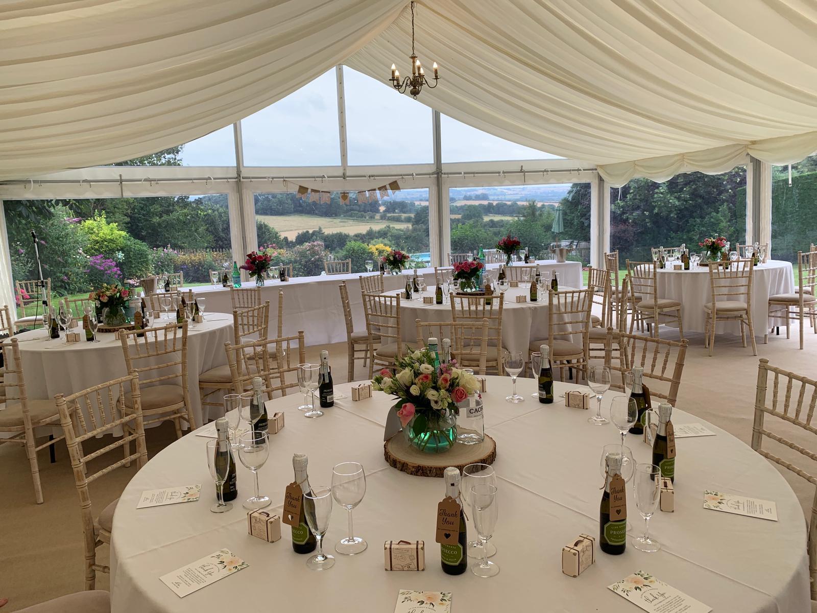 A large tent with tables and chairs set up for a wedding reception.