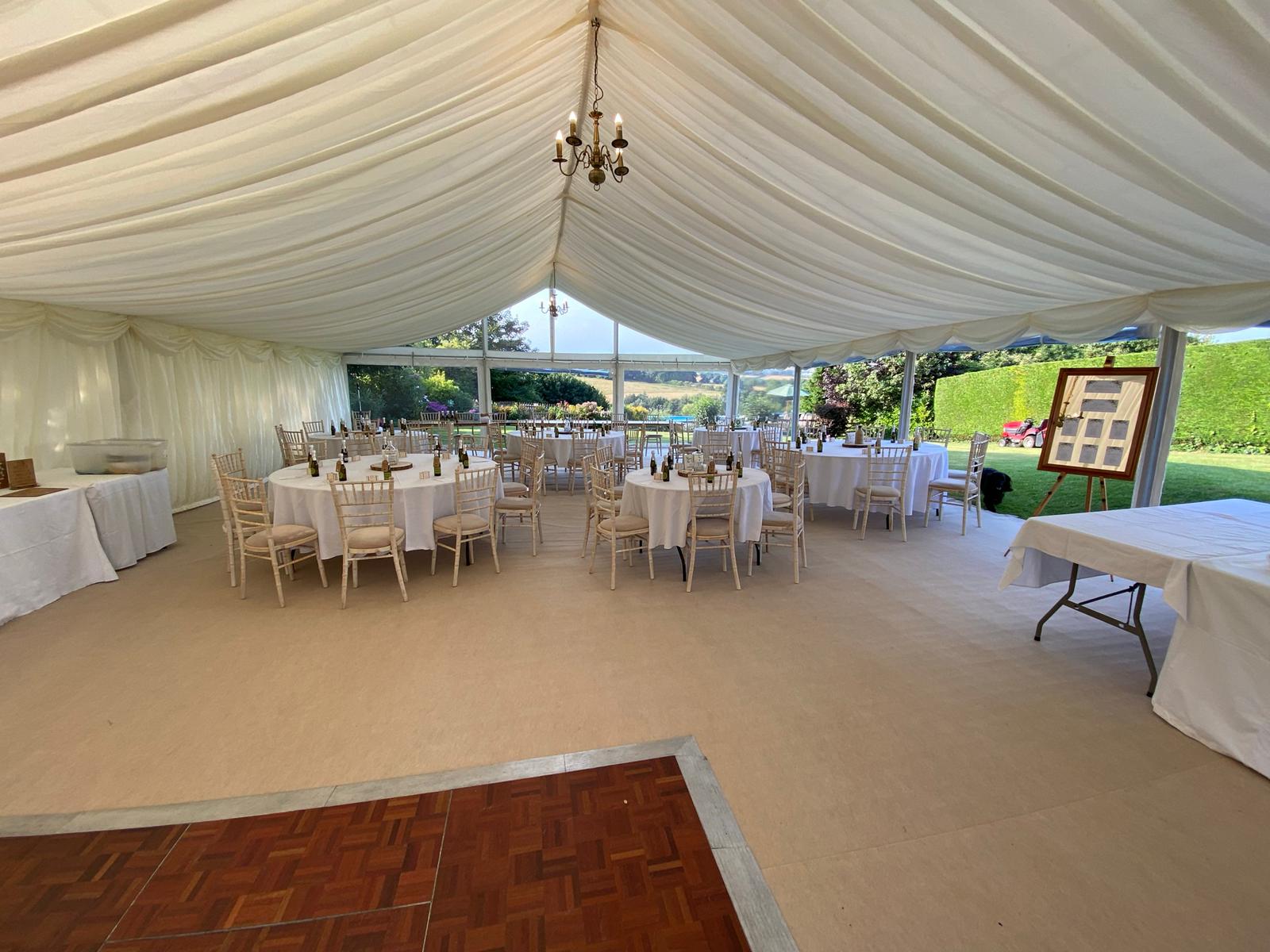 A large tent filled with tables and chairs and a dance floor.