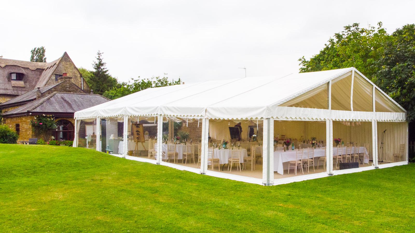 A large white tent is sitting in the middle of a lush green field.