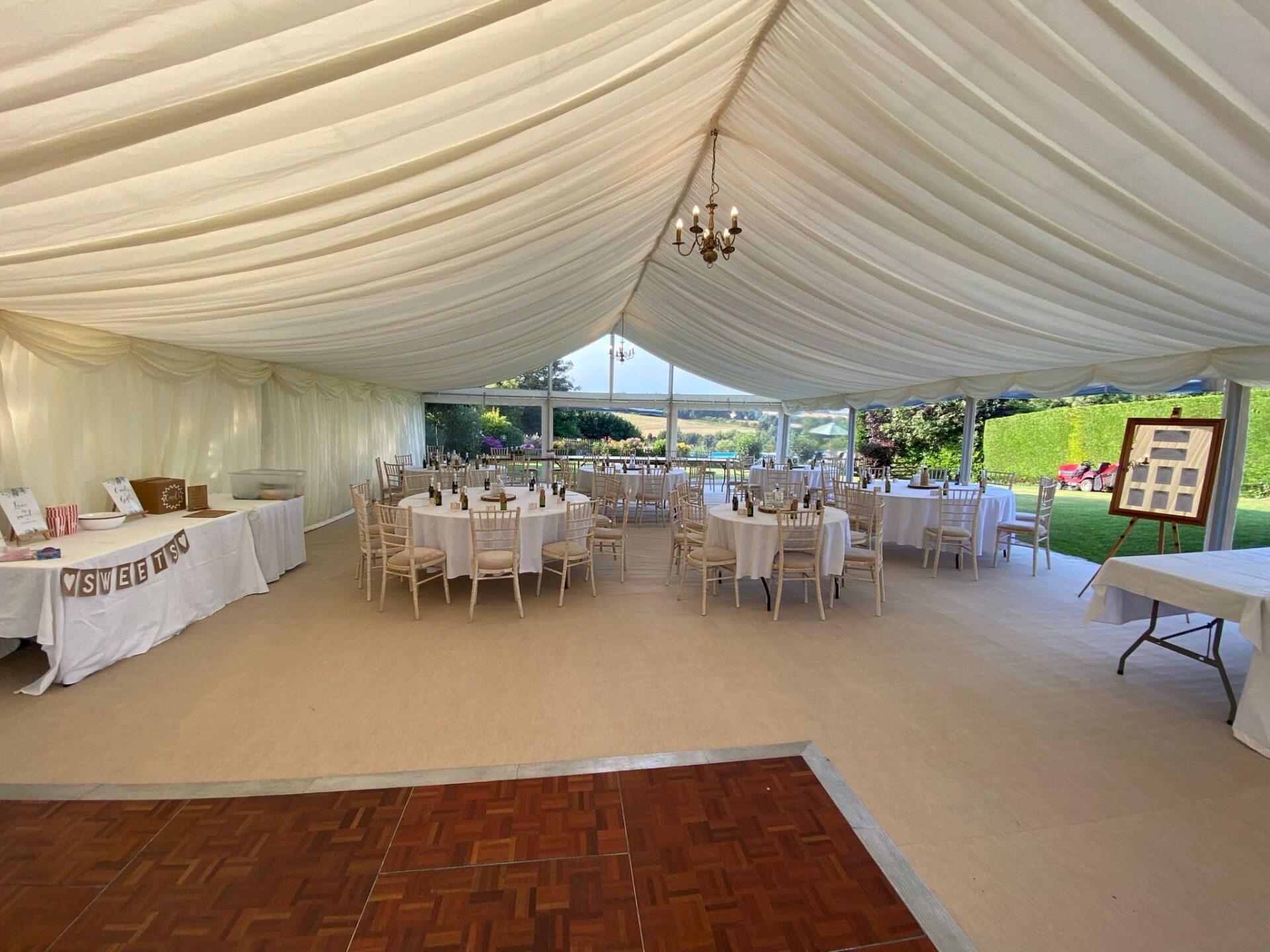 A large tent with tables and chairs set up for a wedding reception.
