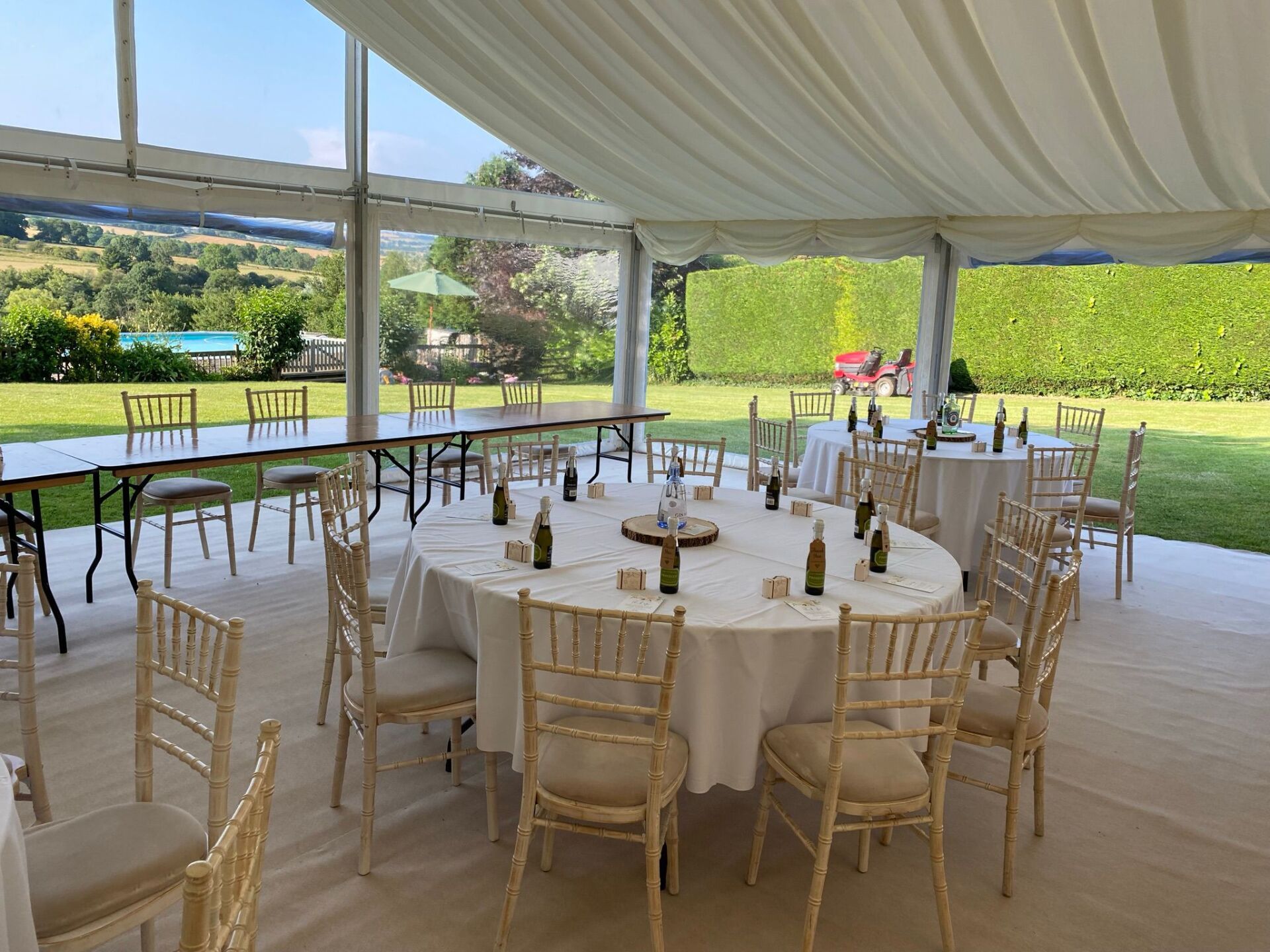 A large tent with tables and chairs set up for a wedding reception.