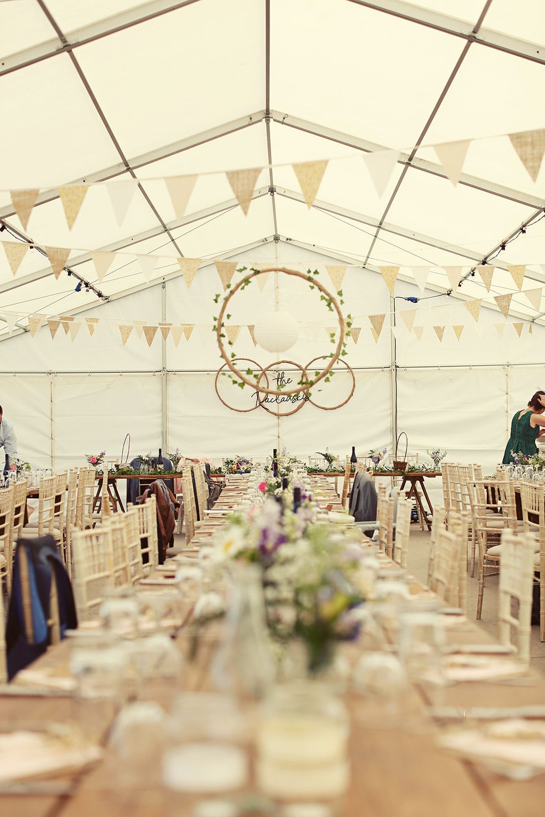 A long table is set up in a tent for a wedding reception.