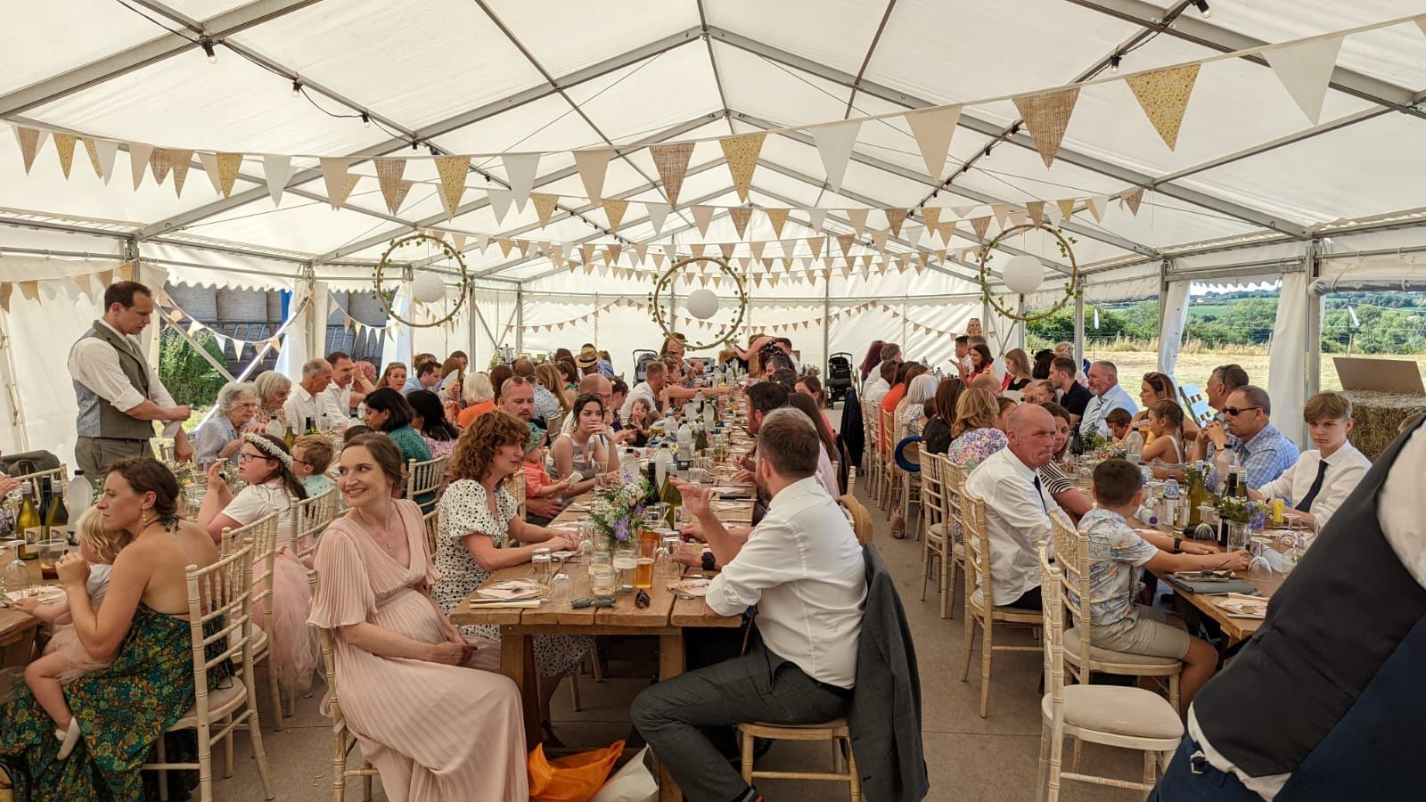 A large group of people are sitting at tables in a tent.
