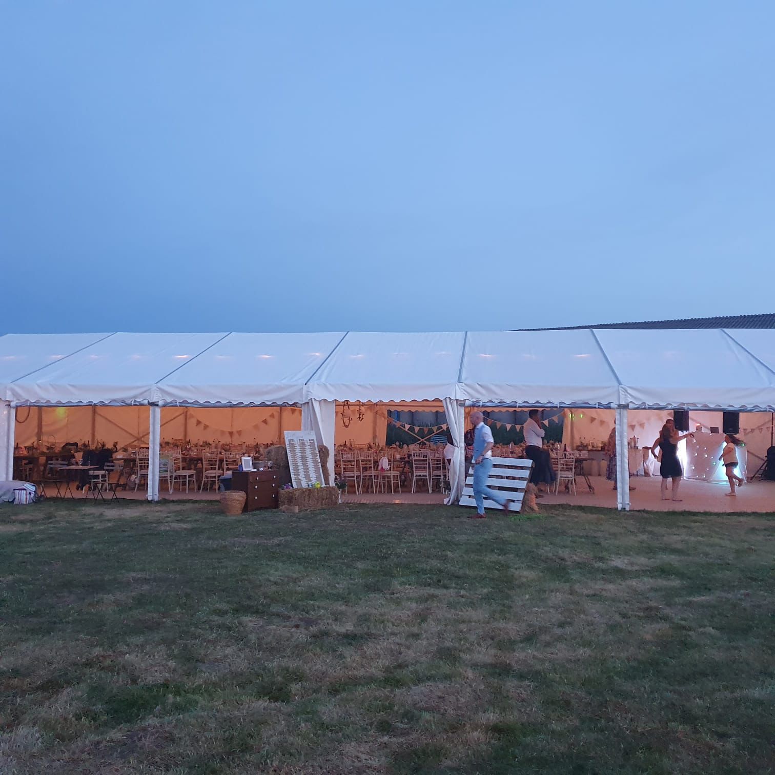A large white tent is sitting in the middle of a grassy field.