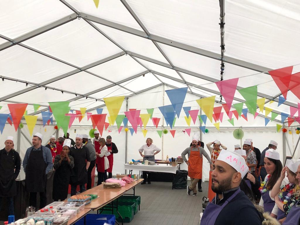 A group of people are standing in a tent with flags hanging from the ceiling.