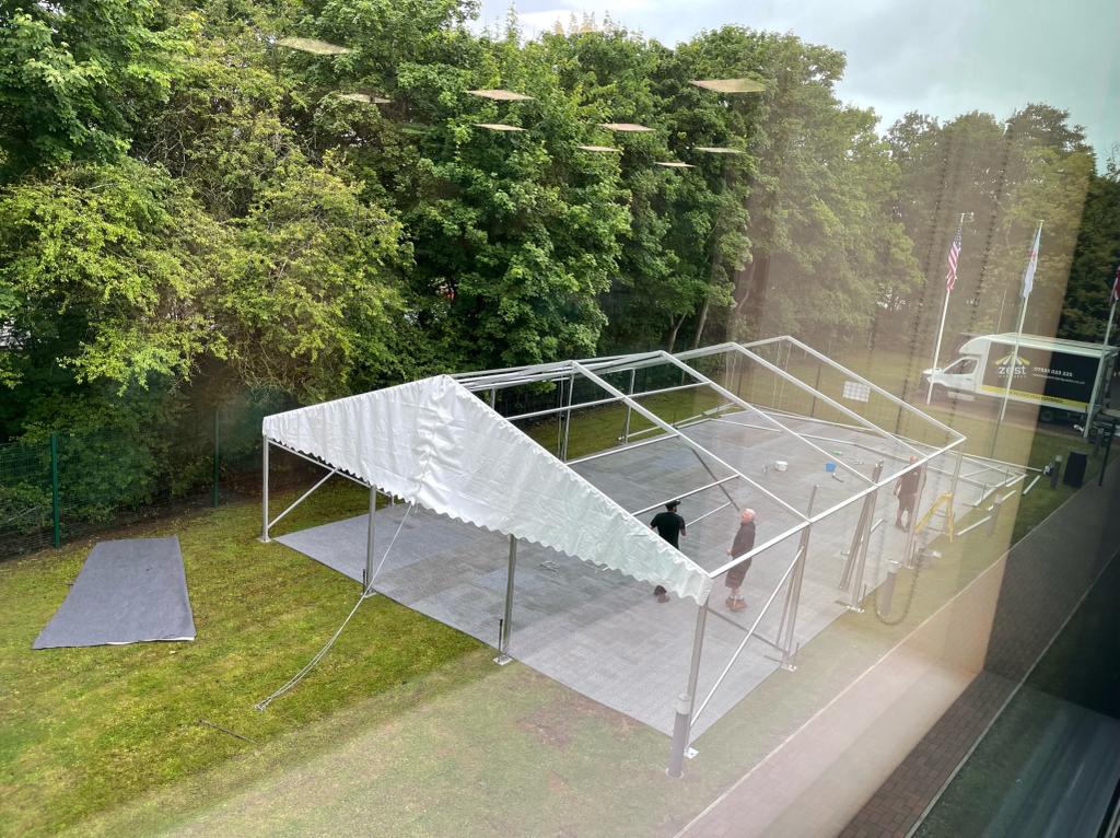 A large white tent is sitting on top of a lush green field.