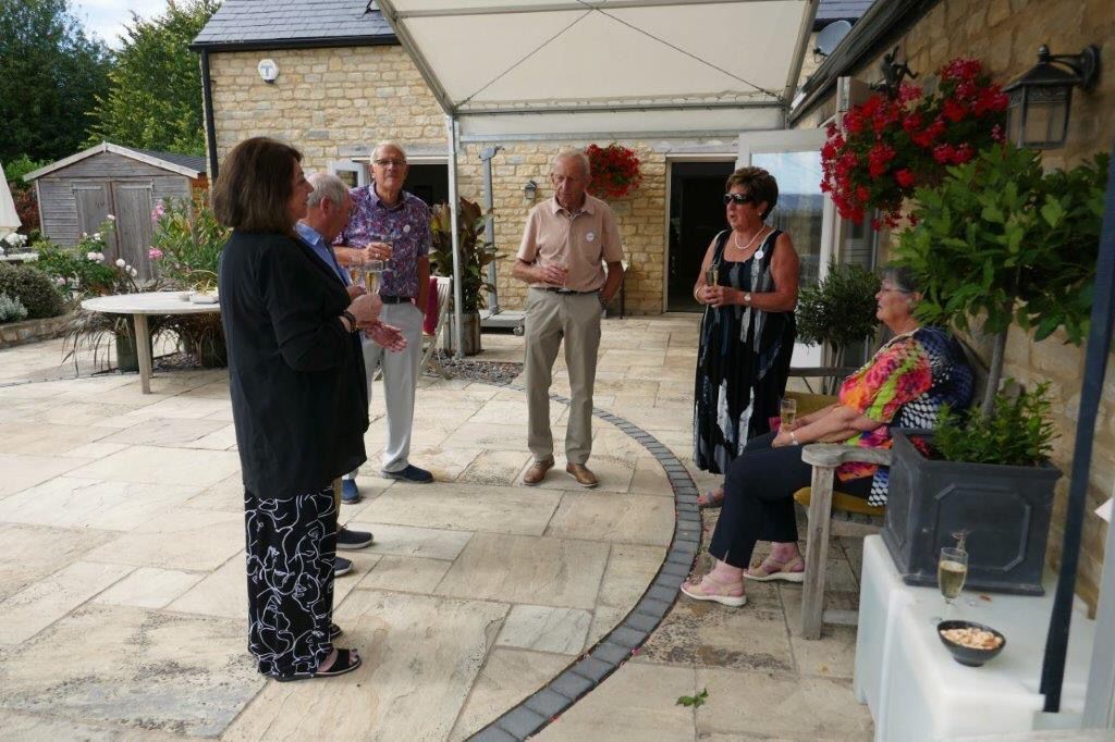 A group of people are standing on a patio talking to each other.