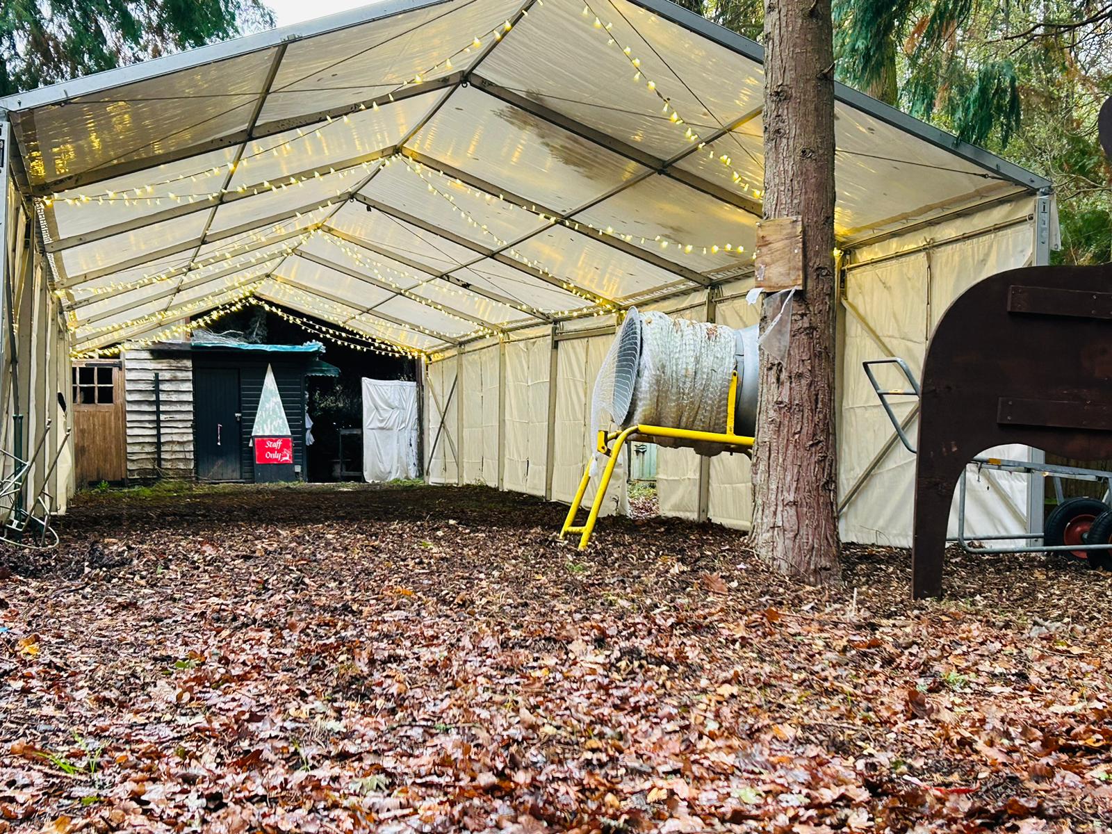 A large white tent with lights on it is sitting on top of a pile of leaves.