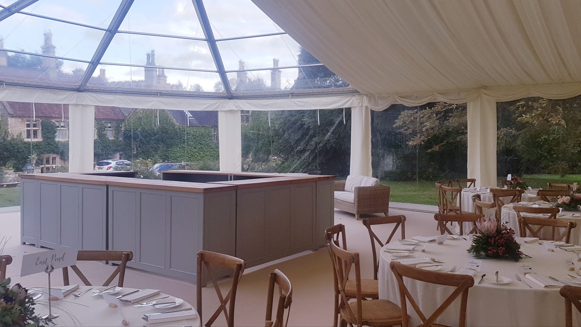 A large tent with tables and chairs and a bar in the middle.