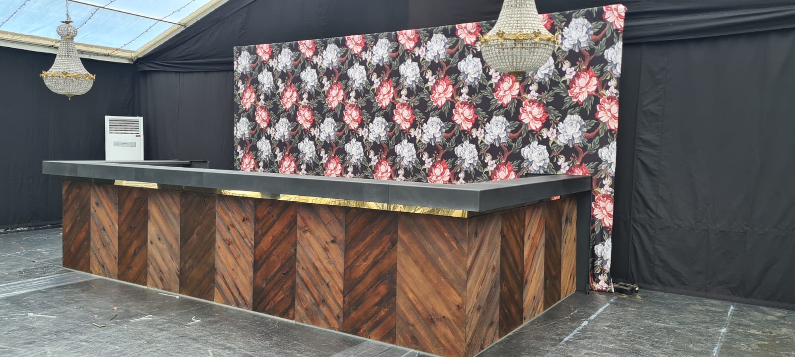 A wooden bar with a floral backdrop in a dark room.