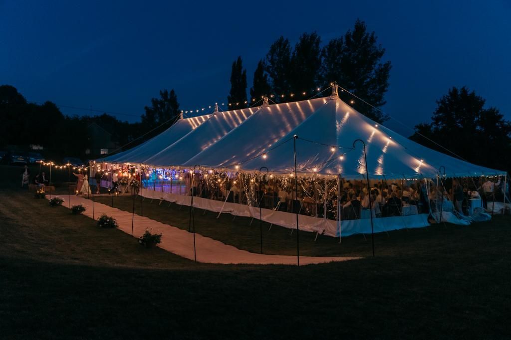 A large tent is lit up at night for a wedding reception.