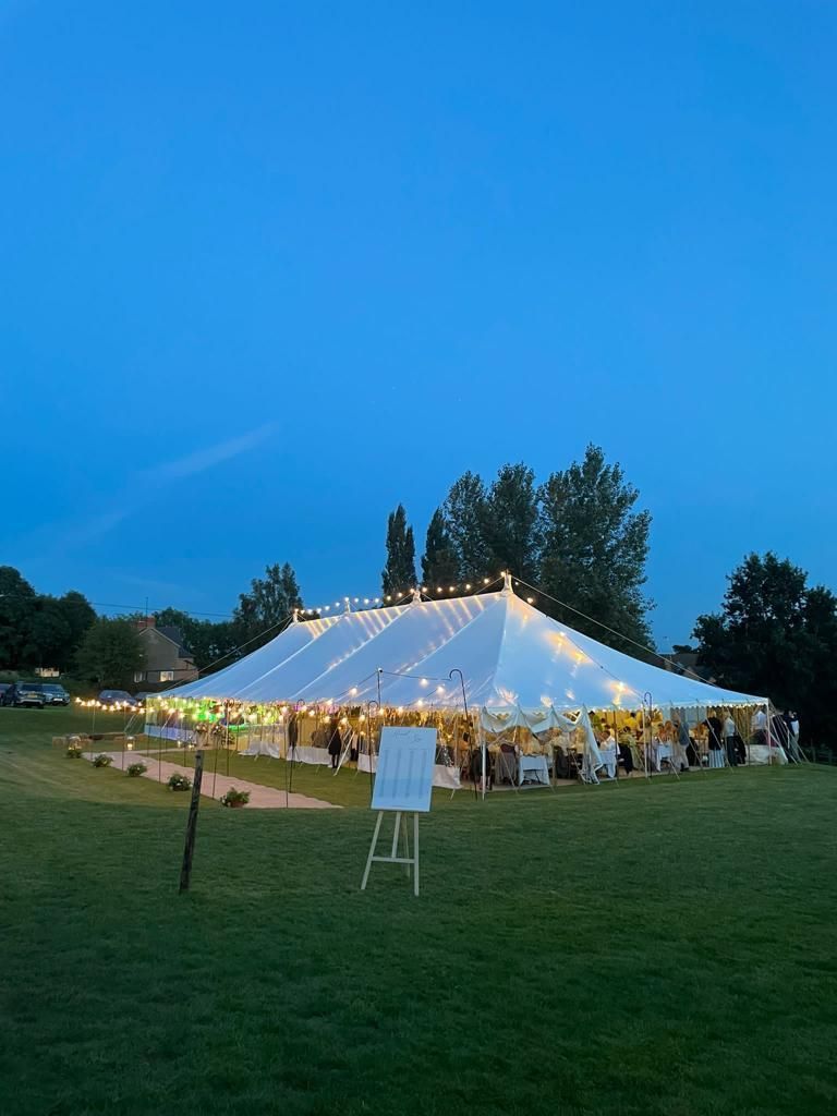 A large white tent is sitting in the middle of a grassy field.