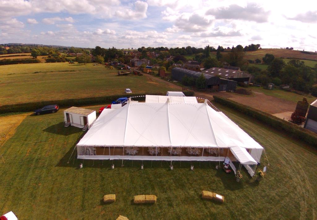 An aerial view of a large white tent in a grassy field